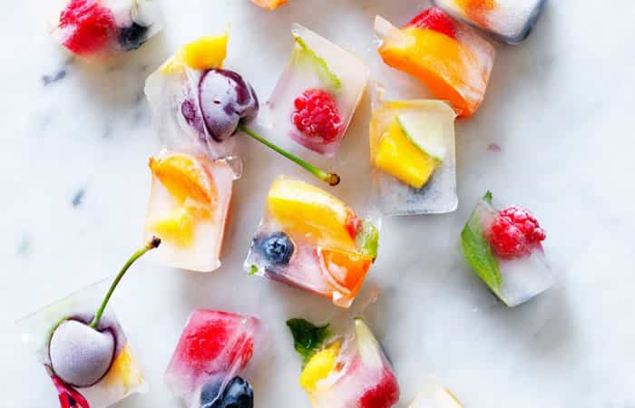 Hielos de colores preparados con fruta, flores comestibles y hierbabuena