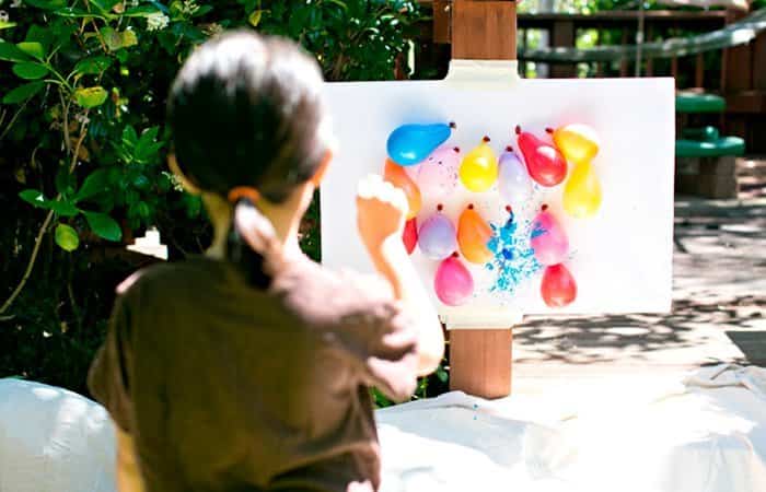 niña tirando dardos a globos llenos de acuarelas dardos con globos puesto en un lienzo