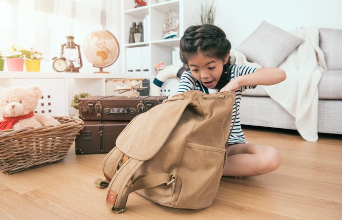 Niña mirando en una mochila con cara de sorpresa Búsqueda del tesoro