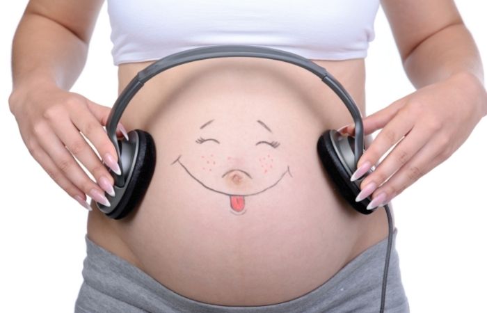ideas para hacer fotos de embarazo divertidas: cara sonriente en la tripa fotos divertidas de embarazo: cara sonriente pintada en la barriga y auriculares
