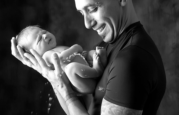 ideas para fotos de tu bebé divertidas: padre sostiene al recién nacido que se hace pis fotos de tu bebé divertidas: se escapa el pis