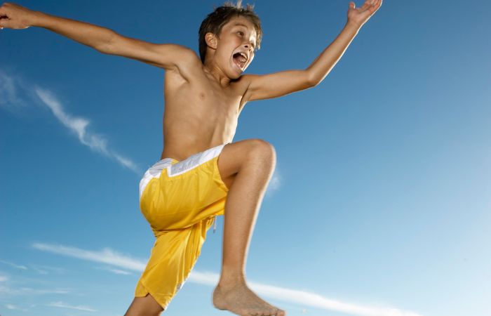 Niño haciendo un salto de longitud en la arena juegos en la playa: salto de longitud