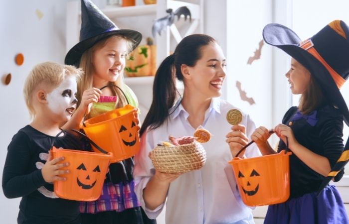 Riesgos de los caramelos en Halloween Mujer dando dulces a unos niños en Halloween