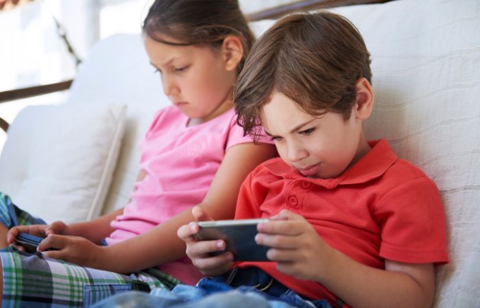Niños con malas posturas mientras miran el móvil, con la cabeza agachada Malas posturas con el móvil