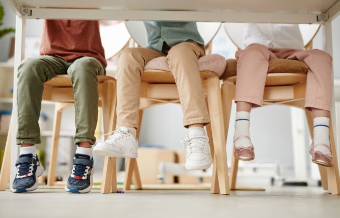 Niños sentados con pies que no llegan al suelo Malas posturas de los niños cuando se sientan
