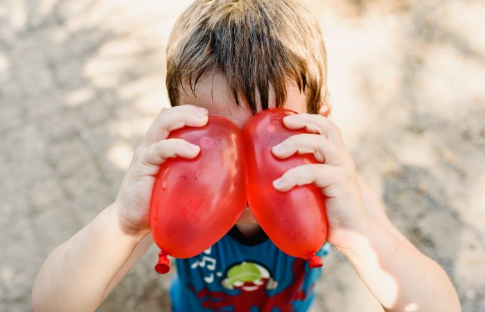 Niño con dos globos de agua pegados en la frente antes de comenzar el juego Juego de globos de agua: pegados en la frente