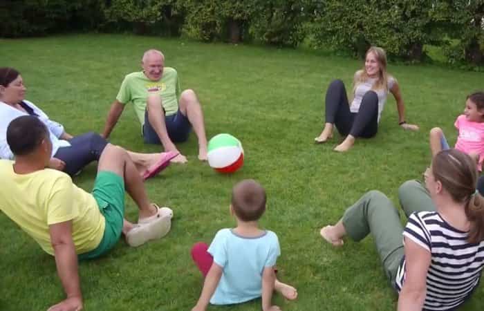Todos en círculo y sentados, jugando a lazar la pelota Balón sentado