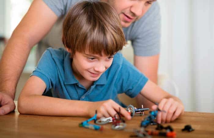 Niño haciendo una actividad extraescolar Niño realizando una manualidad en compañía de su padre