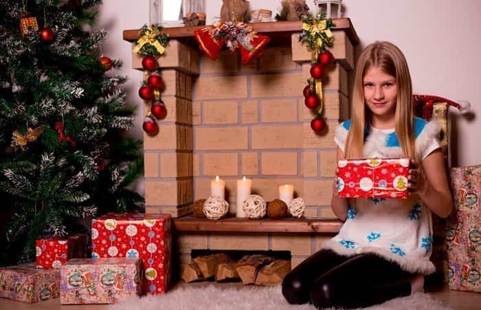 Niña a punto de abrir su regalo de Navidad 