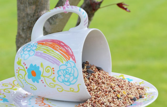 Alpiste en una taza decorada Una taza de loza y un plato para dar alpiste a las aves