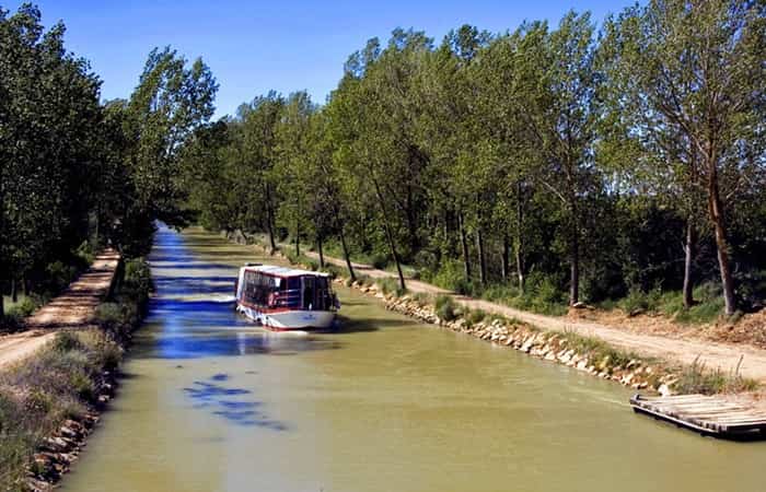 Embarcación turística recorriendo el Canal de Castilla, un modo de navegar en agua dulce embarcación por el Canal de Castilla: navegar en agua dulce