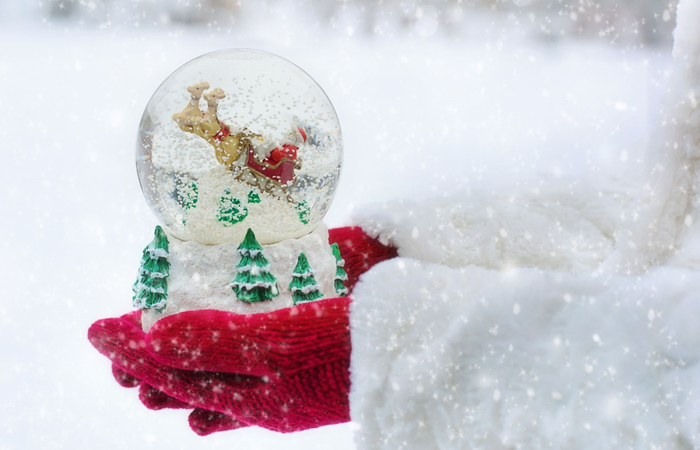 manos sosteniendo bola de cristal con nieve magia de la navidad