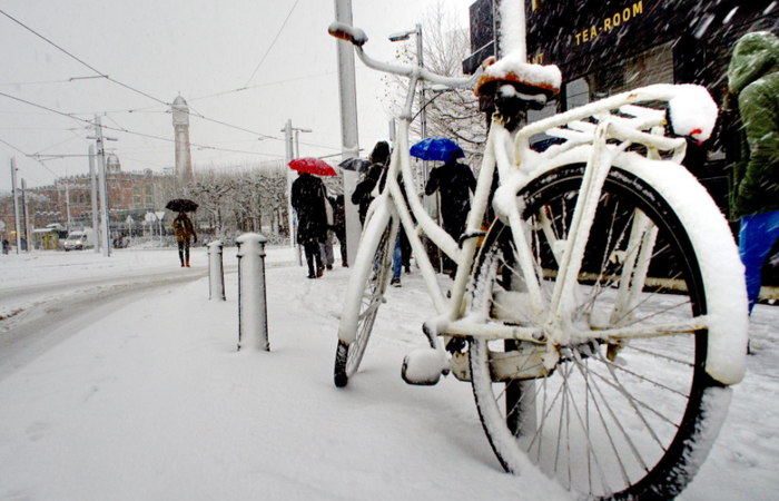 Calle nevada, con transeúntes y bici aparcada Calle nevada
