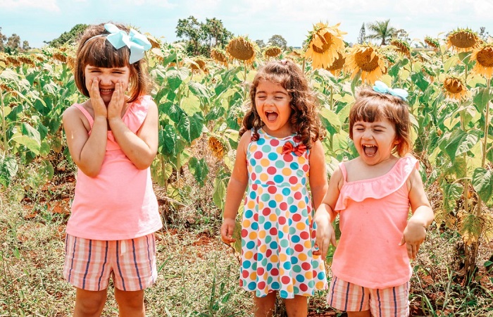 Coger a un bebé en brazos ayuda a los niños a tener una infancia más sociable Tres niñas riendo en un campo de girasoles. Coger a un bebé en brazos: beneficios