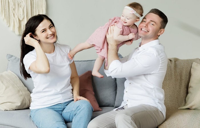 Coger a un bebé en brazos tiene beneficios para su salud y su desarrollo Pareja en un sofá con su bebé. Beneficios a nivel molecular de coger a un bebé en brazos