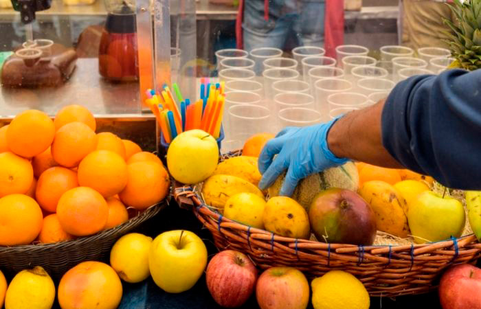 Alergia al látex. Comerciantes en el mercado Mano con guante de látex manipula frutas en el mercado. Alergia al látex.