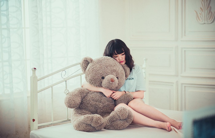 La crianza con violencia Adolescente triste abrazada a un oso grande de peluche. Crianza con violencia