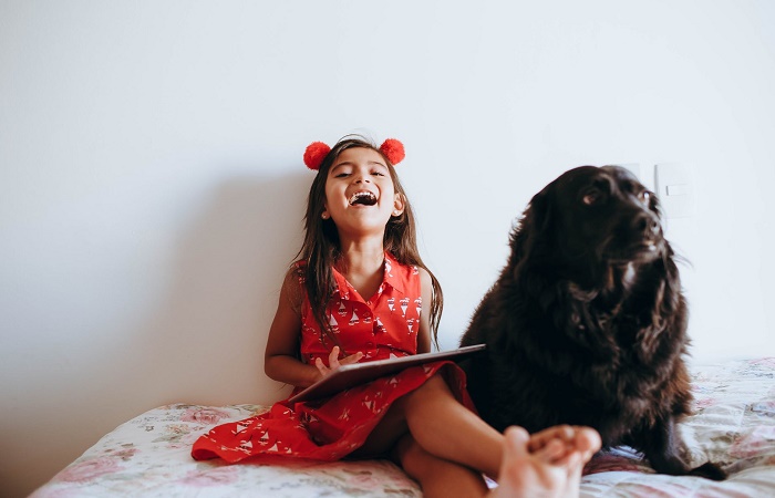 Los perros no deben estar en la habitación de un niño alérgico a la mascota Niña sentada en su cama con el perro a su lado. Alérgico a la mascota síntomas