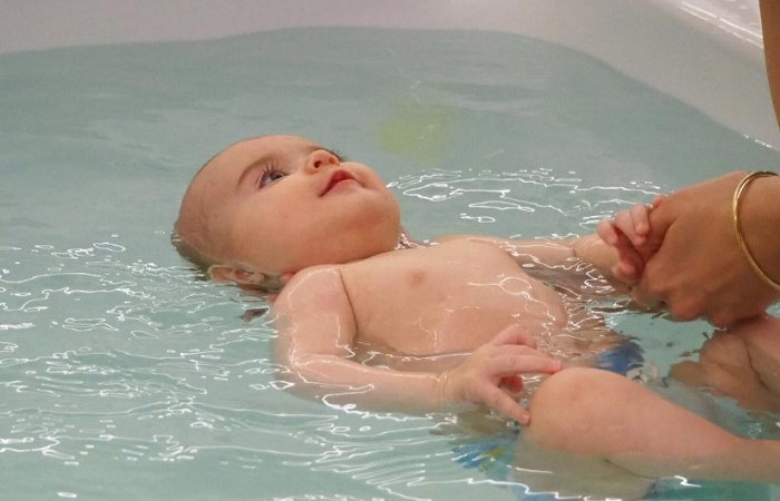 Beneficios de los spas para bebés Niño flotando boca arriba en la bañera de un spa con vigilancia adulta Hidroterapia para bebés
