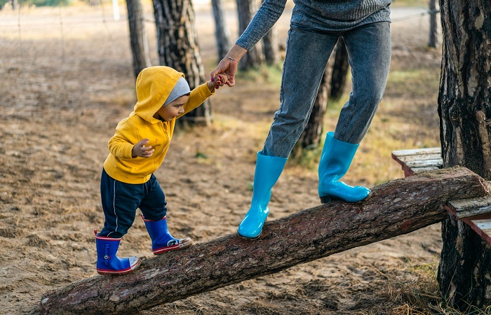 Disfrutar de la naturaleza y jugar con barro Niño con su madre en un parque, con botas de agua Jugar con barro