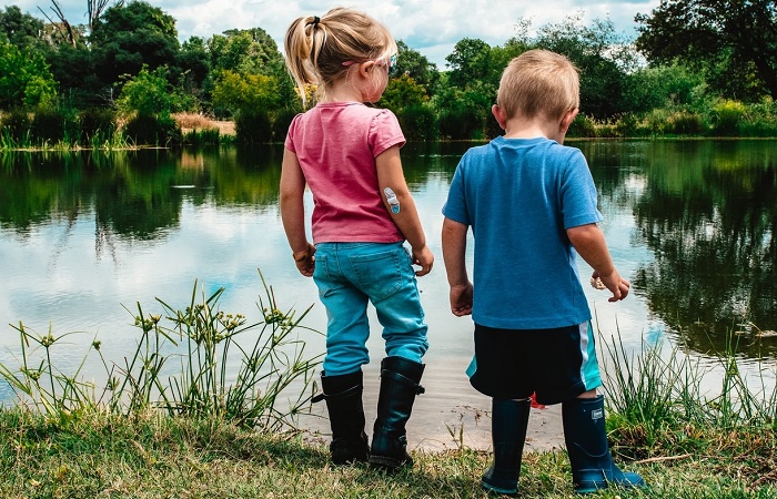Jugar con barro y estar en la naturaleza es positivo Dos niños pequeños frente a un lago. Jugar con barro beneficia su salud