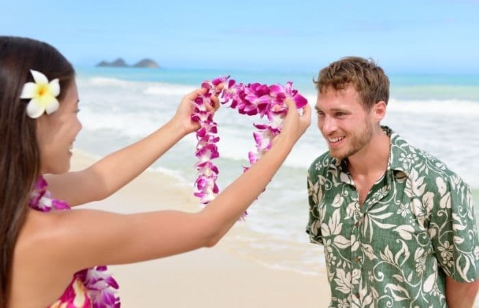Un hombre joven recibe un collar de flores de manos de una hawaiana curiosidades de Hawái