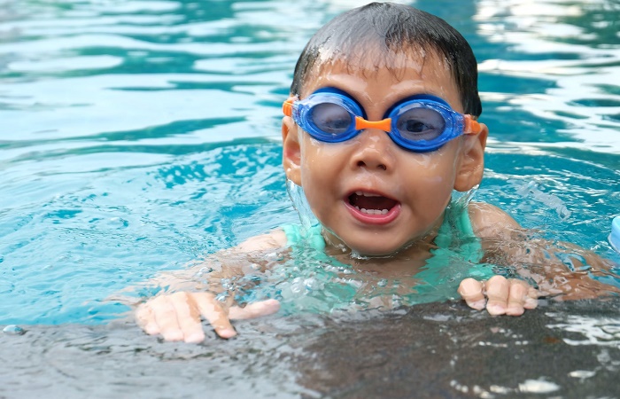 Infecciones de oídos en la piscina Niño en la piscina. Otorrea, síntoma de infección.