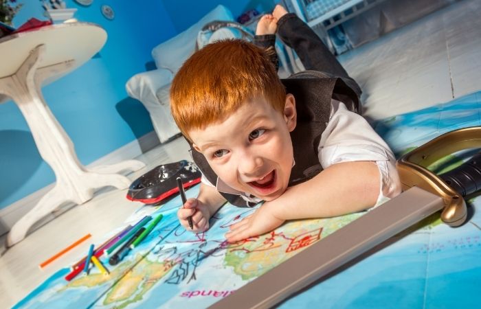 búsqueda del tesoro pirata Niño en el suelo pintando. Ideas para entretener a los niños