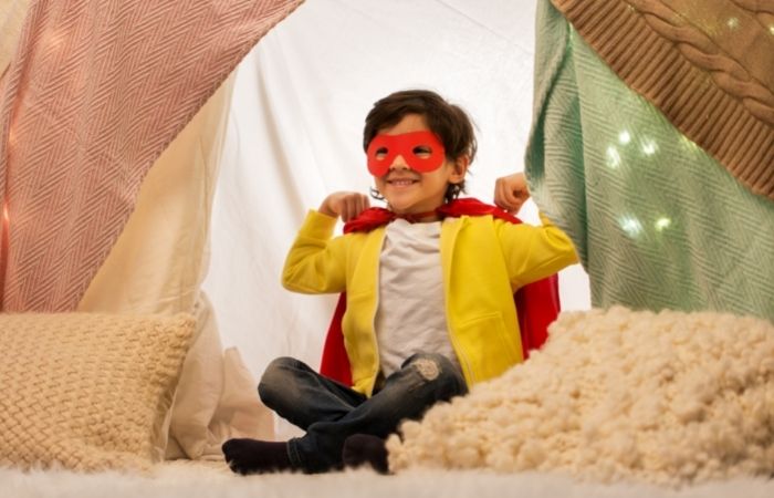 fuerte o cabaña con cojines y colchas Niño ante una cabaña montada con cojines