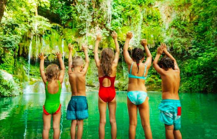 Los ríos, lagos y pantanos son un buen plan para fin de curso Niños en bañador, de espaldas, miran a un lago. Planes para fin de curso