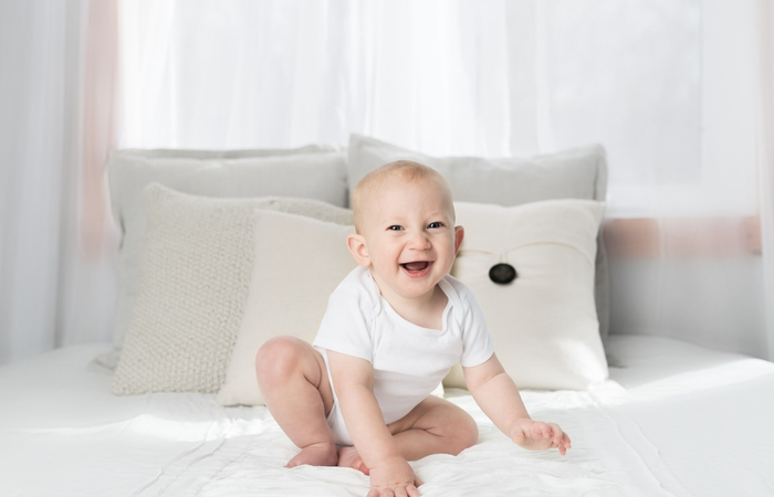imagen bebé riendo sobre una cama nombres originales de niño: bebé riendo
