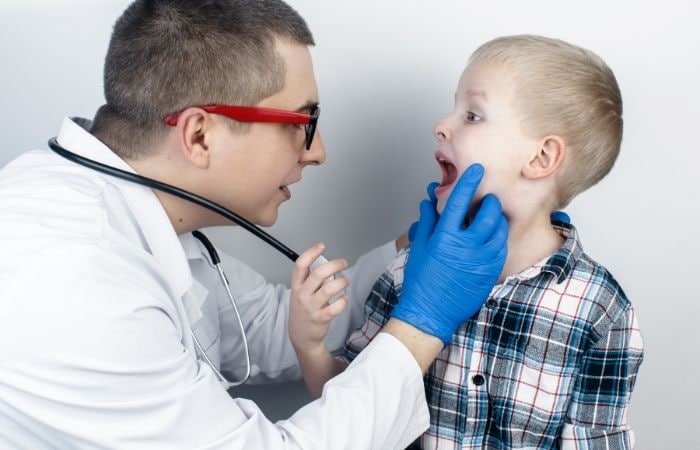 Muguet: médico observando la cavidad bucal de un niño Muguet médicos