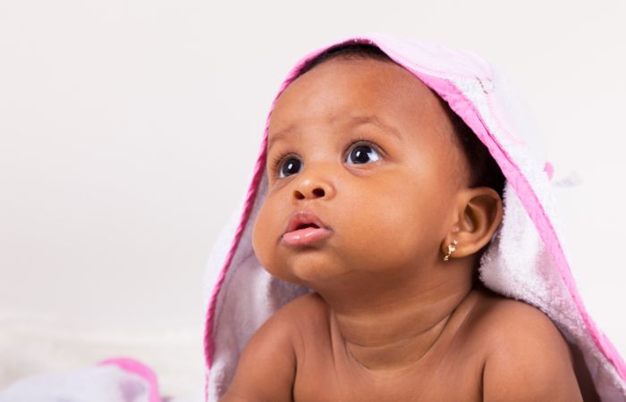 bebé mirando a a alguien apoyada en sus brazos Nombres originales de niña para tu bebé