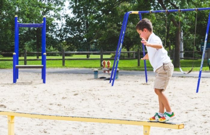 desarrollo de la creatividad jugando en el parque jugar en el parque: niño en la zona recreativa caminando por una barra