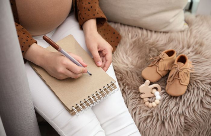 Madre embarazada anotando nombres en un cuaderno Haz una lista con nombres originales de niña