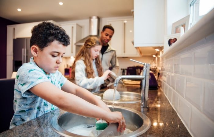 Hijo e hija, fregando los paltos ante la mirada de su padre, una iniciativa contra niños vagos niños vagos: incentiva la colaboración en las tareas del hogar