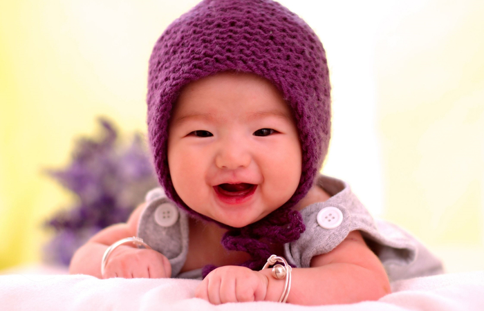 bebé sonriente con gorrito morado bebé sonriente