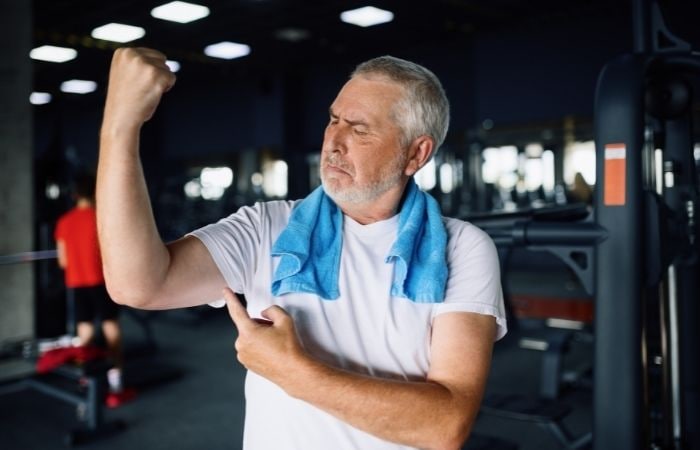 La midorexia puede afectar la vida social de las personas Midorexia: hombre maduro en el gimnasio observa su bíceps