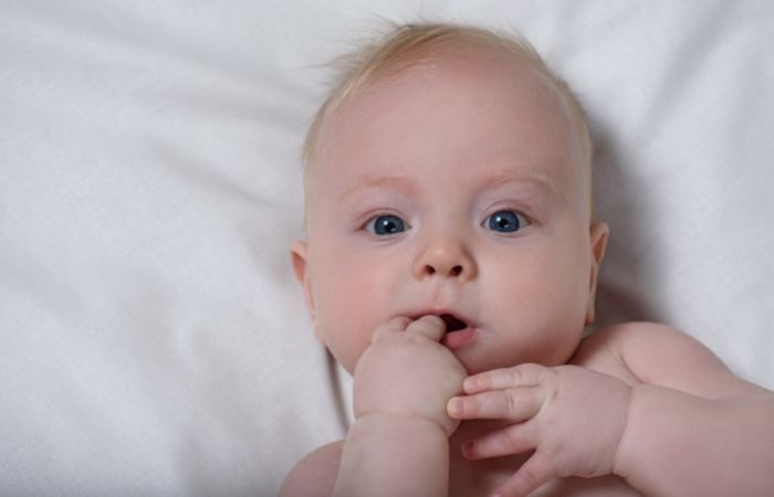 niño pequeño tumbado Nombres gallegos de niños: bebé tumbado, desnudito, chupándose la manita.
