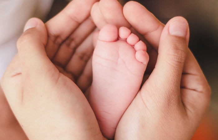 pie de bebé entre manos nombres catalanes de niño: pie de bebé