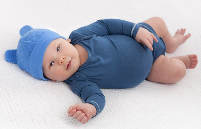 bebé tumbado con body azul nombres guanches de niño: bebé con body y gorrito azules