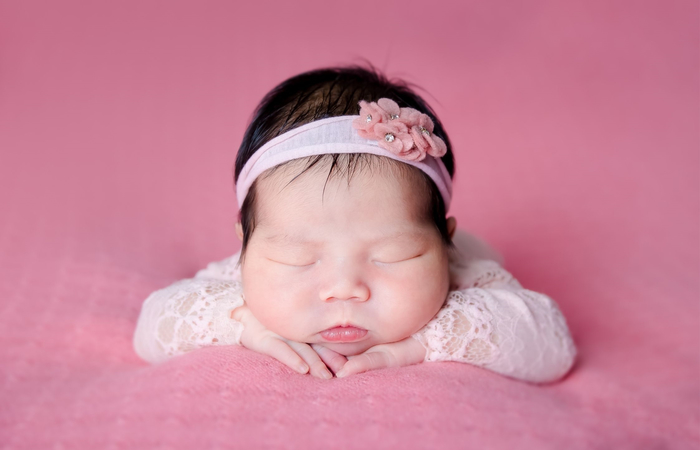 bebé sobre colcha rosa bebé dormida, con diadema y sobre colcha rosa