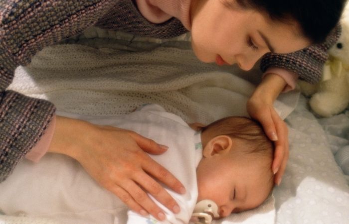 Tocar al bebé cada poco tiempo, una de las señales de TOC postparto Trastorno Obsesivo Compulsivo postparto: madre tocando con precaución a su bebé dormido en la cuna