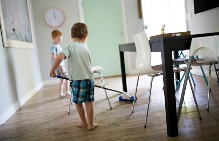 Delegar en casa significa dejar que se impliquen en la medida de sus posibilidades Delegar en casa: niño limpiando suelo de la cocina