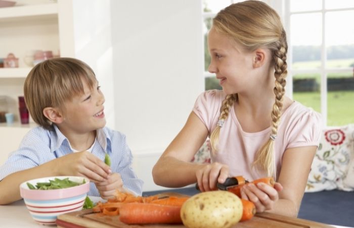 Delegar en casa: colaborar en la preparación de las comidas Delegar en casa: niña y niño limpiando verduras