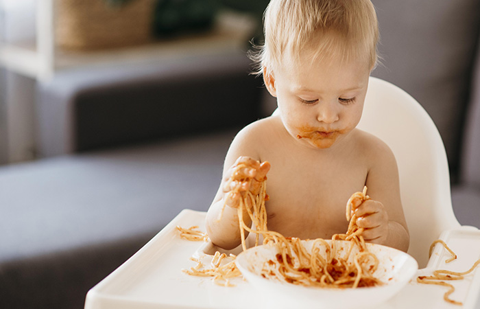 Ármate de paciencia para enseñar a los niños a comer solos bebé comiendo espaguetis con tomate con sus manos