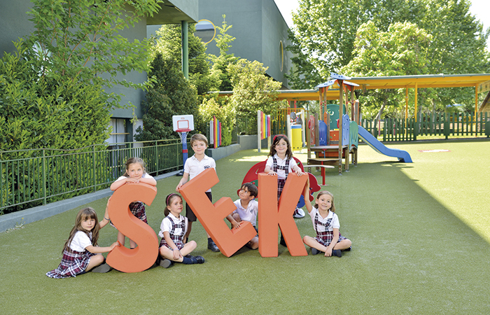 Niños y niñas sujetando las letras S Colegios SEK