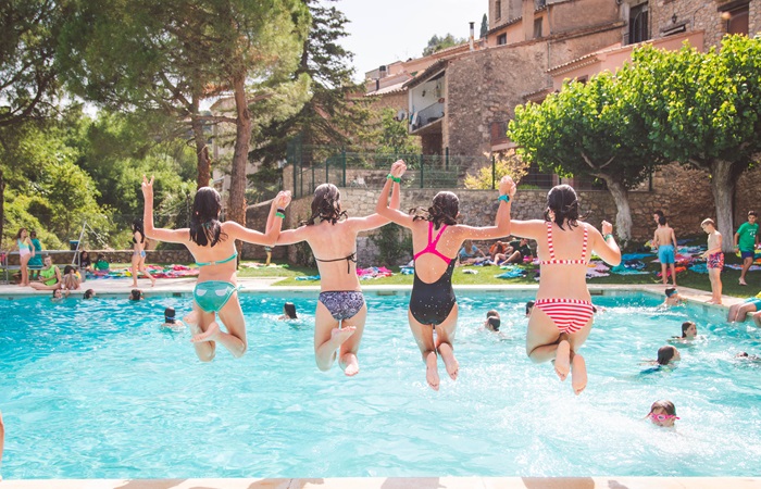 Amigas saltando a la piscina de la mano Diversión en la piscina en English Summer