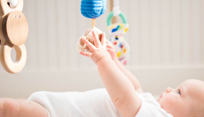 El bebé trata de coger con su mano las figuras del móvil Móviles para cuna: beneficios