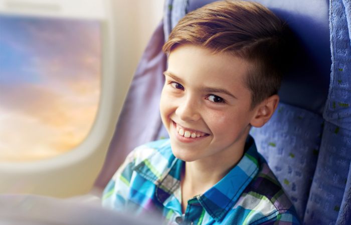 Niño sonriente que viaja solo en un avión Niños que viajan solos en avión